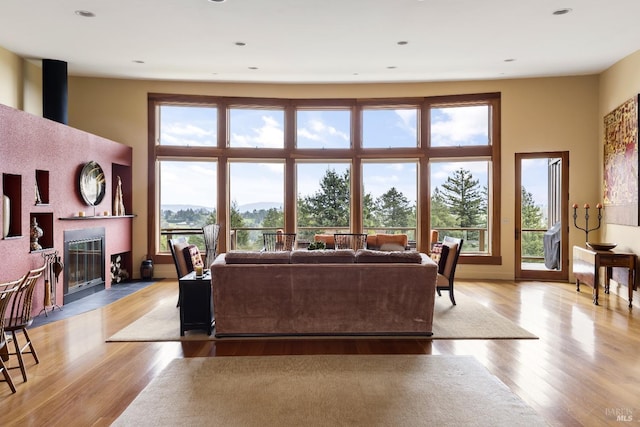 living area featuring a fireplace with flush hearth, light wood-style floors, a mountain view, and recessed lighting