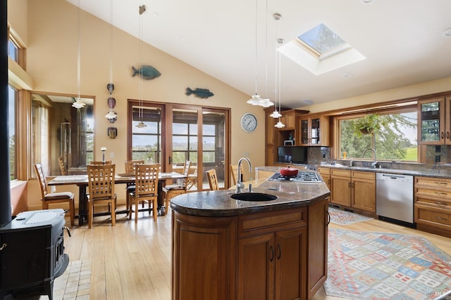 kitchen featuring appliances with stainless steel finishes, plenty of natural light, brown cabinetry, a skylight, and a sink