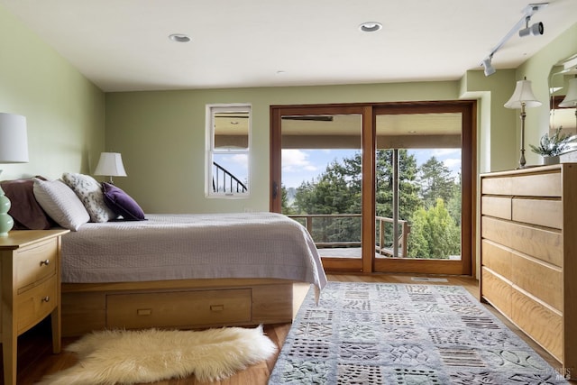 bedroom with recessed lighting, track lighting, access to outside, and wood finished floors