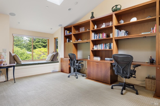 office space featuring vaulted ceiling with skylight, visible vents, and light colored carpet