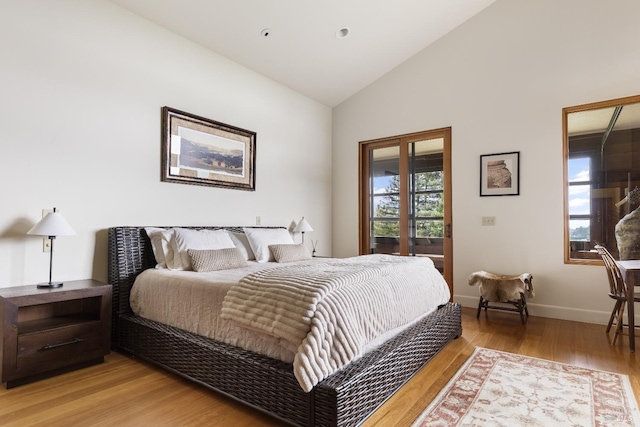 bedroom featuring light wood-type flooring, baseboards, and lofted ceiling