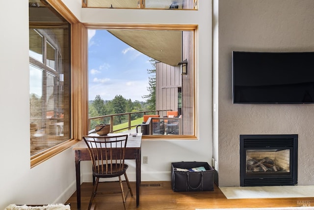 dining area with visible vents, baseboards, a glass covered fireplace, and wood finished floors