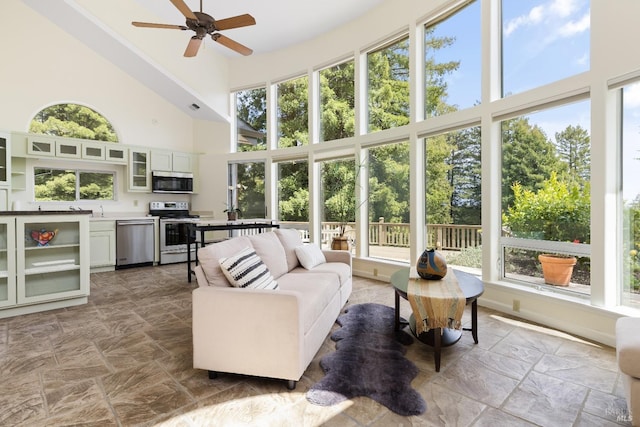 sunroom / solarium featuring a high ceiling and stone finish flooring