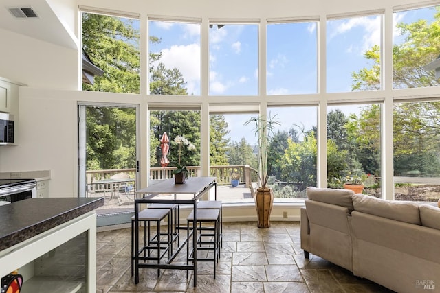 interior space with wine cooler, visible vents, and stone tile floors