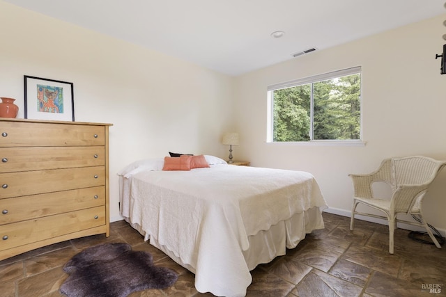 bedroom with visible vents, baseboards, and stone tile flooring