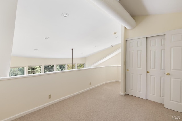 interior space with a closet, light colored carpet, and baseboards