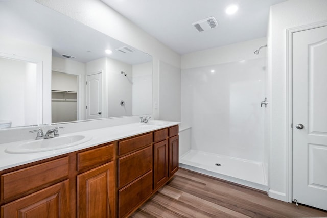 bathroom featuring a sink, visible vents, a stall shower, and wood finished floors