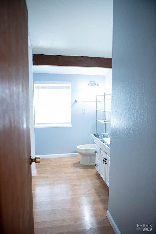bathroom with toilet, wood finished floors, vanity, and baseboards