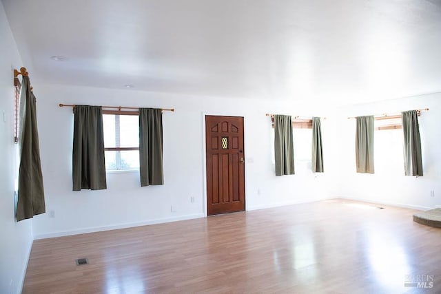 unfurnished room with baseboards, visible vents, and wood finished floors