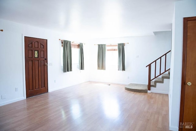 unfurnished living room with stairway, wood finished floors, and baseboards