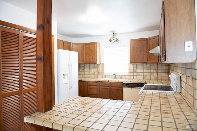 kitchen featuring tasteful backsplash, white appliances, tile countertops, and range hood