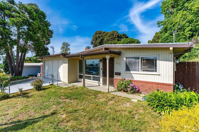 view of front of home with an attached garage, a front lawn, and fence