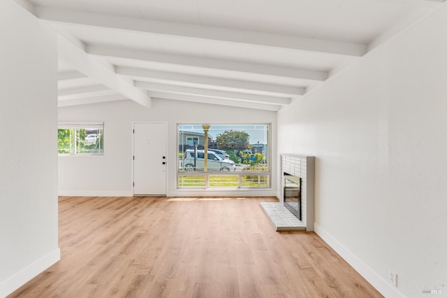 unfurnished living room featuring vaulted ceiling with beams, baseboards, wood finished floors, and a fireplace