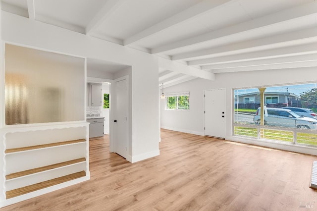 spare room with baseboards, vaulted ceiling with beams, and light wood-type flooring