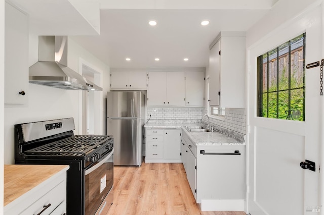 kitchen featuring a sink, appliances with stainless steel finishes, plenty of natural light, and wall chimney exhaust hood