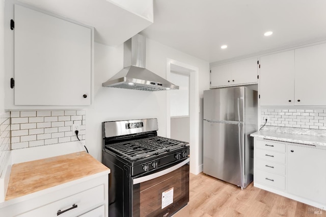 kitchen with light countertops, wall chimney exhaust hood, light wood-style flooring, backsplash, and stainless steel appliances