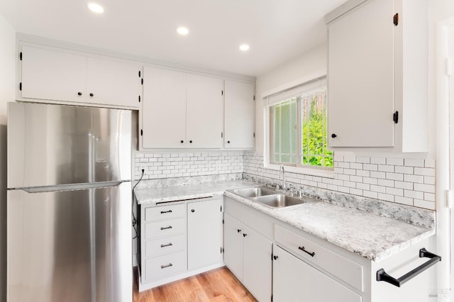 kitchen with recessed lighting, freestanding refrigerator, a sink, and light countertops