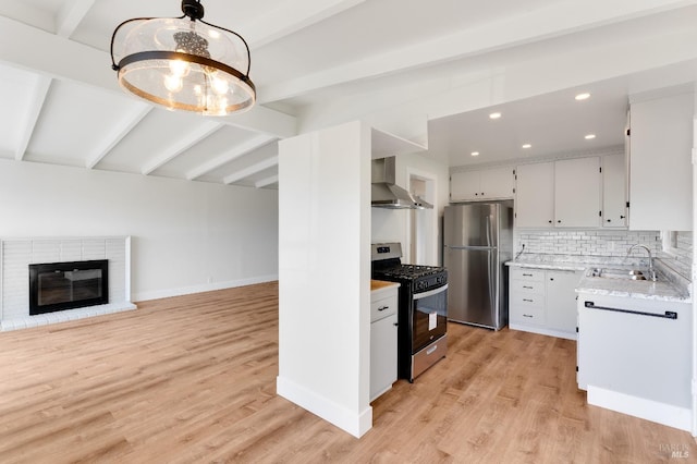 kitchen with a sink, wall chimney exhaust hood, light wood-style flooring, and stainless steel appliances