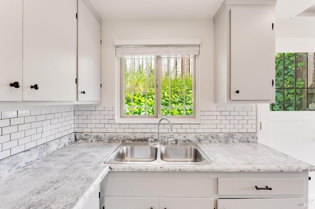 kitchen featuring light countertops, backsplash, a healthy amount of sunlight, and a sink