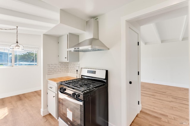 kitchen featuring wall chimney range hood, white cabinets, stainless steel gas range oven, light wood-style floors, and light countertops