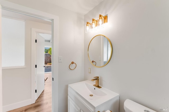 bathroom featuring vanity, baseboards, wood finished floors, and toilet