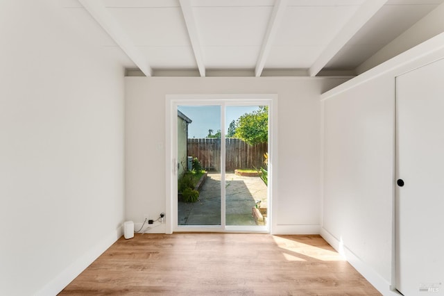 unfurnished room with beam ceiling and light wood-type flooring