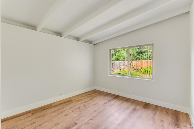 spare room with baseboards, vaulted ceiling with beams, and light wood-type flooring