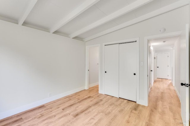 unfurnished bedroom with light wood-style floors, baseboards, vaulted ceiling with beams, and a closet
