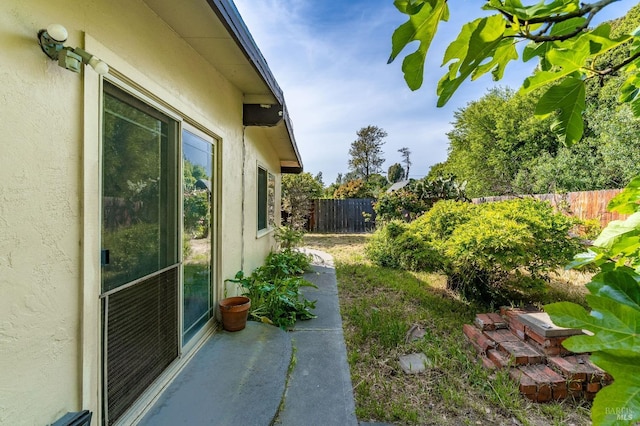 view of side of property with a fenced backyard and stucco siding
