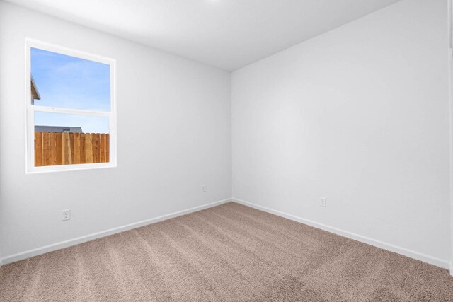spare room with baseboards and carpet