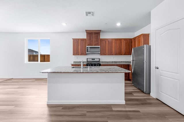 kitchen with visible vents, light stone countertops, light wood finished floors, and stainless steel appliances