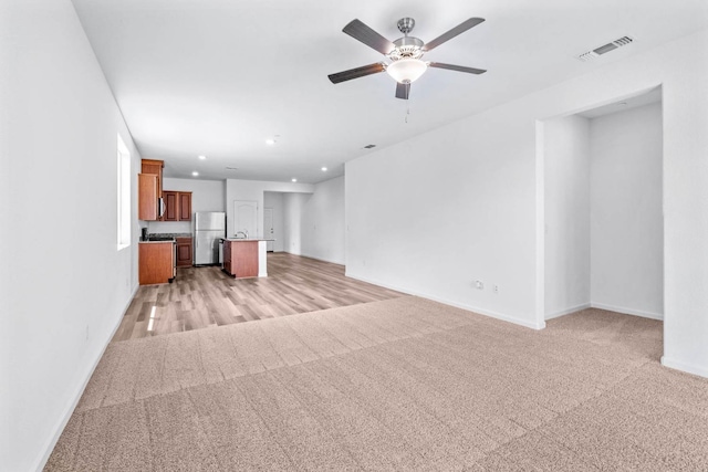 unfurnished living room featuring visible vents, baseboards, a ceiling fan, recessed lighting, and light colored carpet