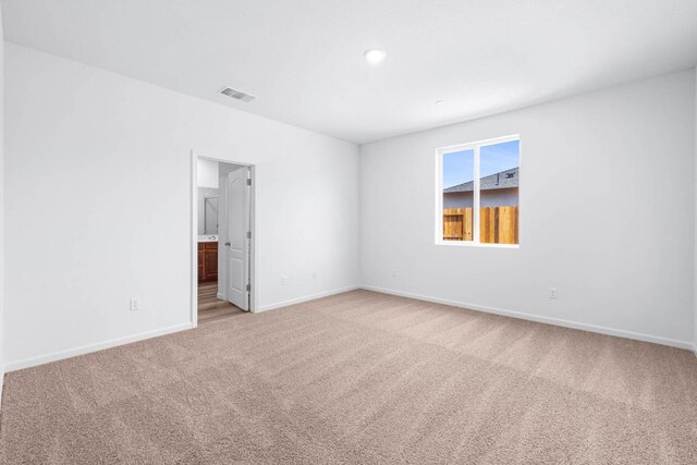 carpeted spare room with visible vents and baseboards