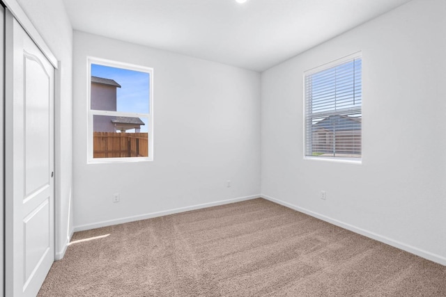 unfurnished room with baseboards and carpet flooring