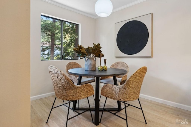 dining space featuring ornamental molding, baseboards, and light wood finished floors