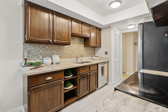 kitchen featuring light tile patterned flooring, a sink, backsplash, appliances with stainless steel finishes, and baseboards