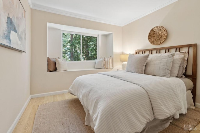 bedroom with ornamental molding, baseboards, and wood finished floors