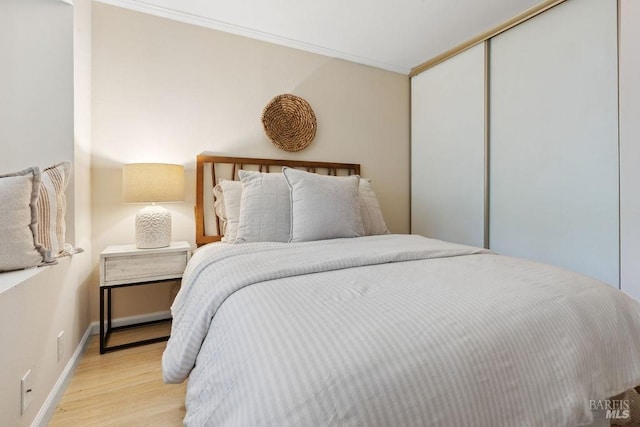 bedroom featuring a closet, baseboards, ornamental molding, and wood finished floors