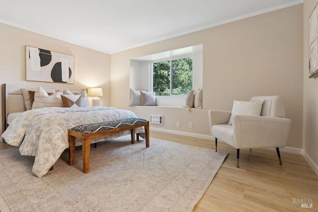 bedroom with baseboards, visible vents, light wood-style floors, and ornamental molding