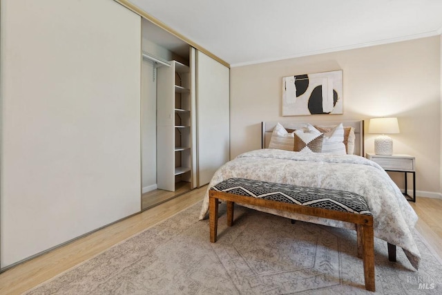 bedroom featuring baseboards, light wood-type flooring, a closet, and ornamental molding