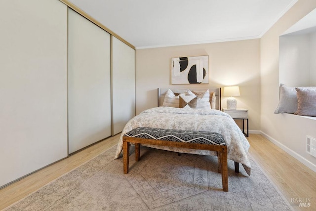 bedroom with baseboards, a closet, crown molding, and wood finished floors