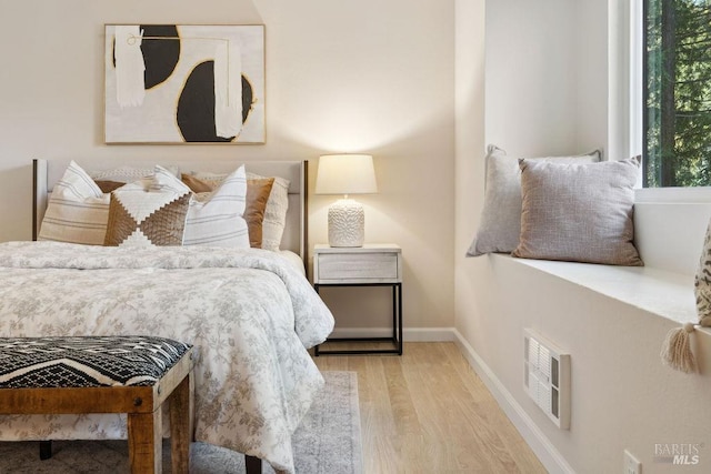 bedroom with wood finished floors, baseboards, and visible vents