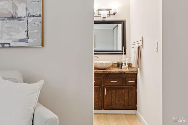 bathroom featuring baseboards, wood finished floors, and vanity
