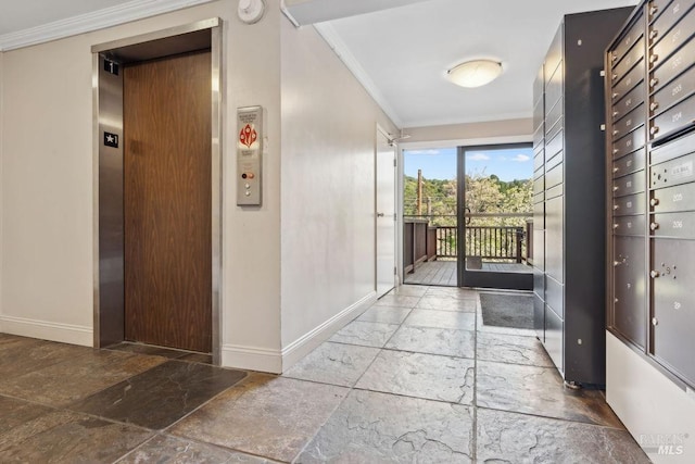 hallway with elevator, stone tile flooring, ornamental molding, and baseboards