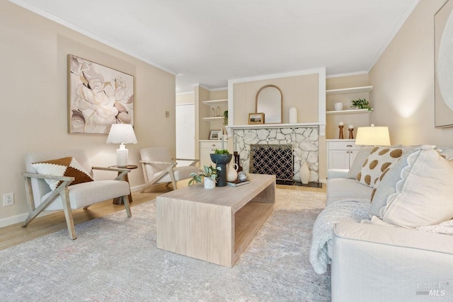living area featuring crown molding, baseboards, a fireplace, wood finished floors, and built in shelves