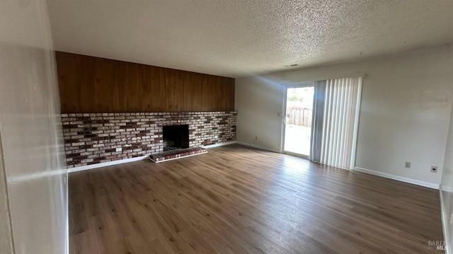 175 Nehoc Ct, Ukiah, CA 95482 - unfurnished living room with a brick fireplace, visible vents, a textured ceiling, and wood finished floors