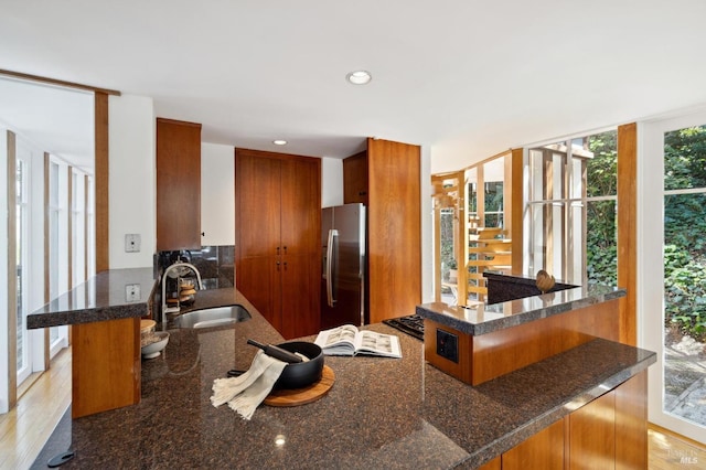 45 Bella Vista Ave, Belvedere, CA 94920 - kitchen with a peninsula, brown cabinets, dark stone countertops, a sink, and stainless steel refrigerator with ice dispenser