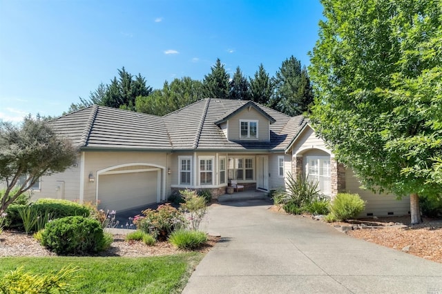 traditional-style home with crawl space, a tile roof, a garage, and driveway
