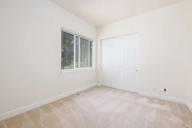 interior space featuring baseboards, visible vents, and light colored carpet