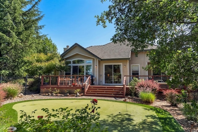 back of house featuring a chimney, a deck, and fence